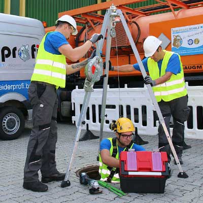 Monteur im Ölabscheider, gesichert mit Dreifuss